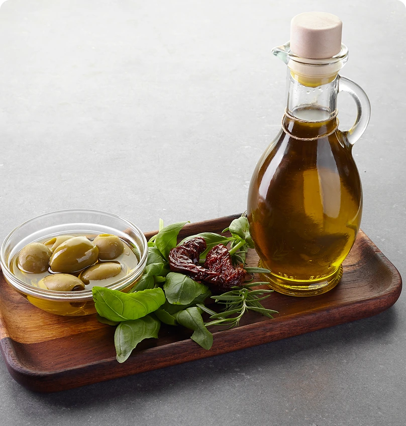 GettyImages-1185497617 Olive oil, olives, herbs on wooden tray.