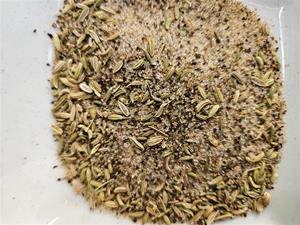 Ground spices and seeds on white surface.