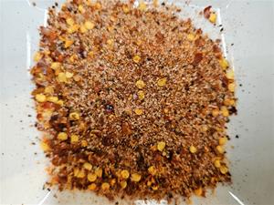 Ground spices and chili flakes in dish.